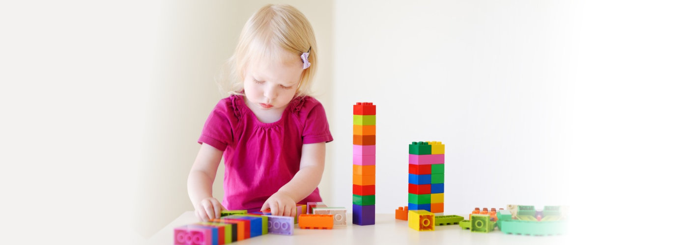 little toddler girl playing with colorful plastic blocks